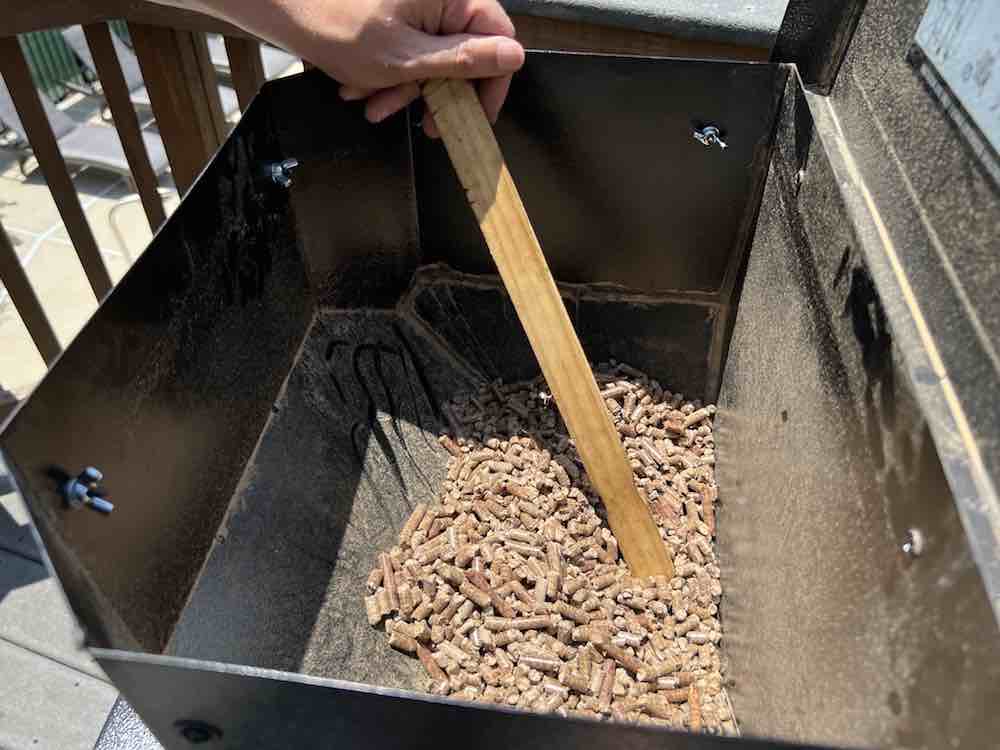 moving pellets towards auger with paint stick