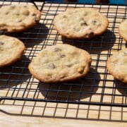 smoked chocolate chip cookies on a wire cooling rack set over a wooden cutting board