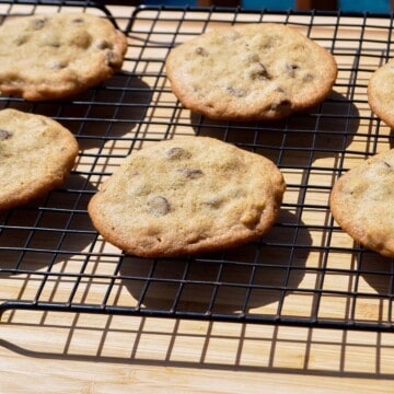 smoked chocolate chip cookies on a wire cooling rack set over a wooden cutting board