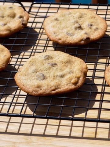 smoked chocolate chip cookies on a wire cooling rack set over a wooden cutting board