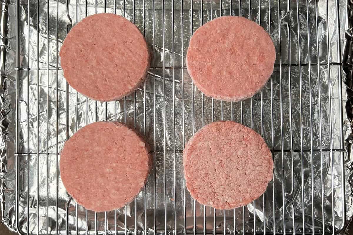 Frozen uncooked hamburgers on a wire baking rack
