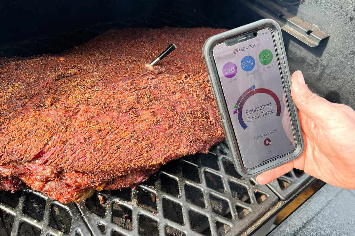 MEATER probe inserted into beef brisket with an iPhone in front of it with the MEATER app displayed