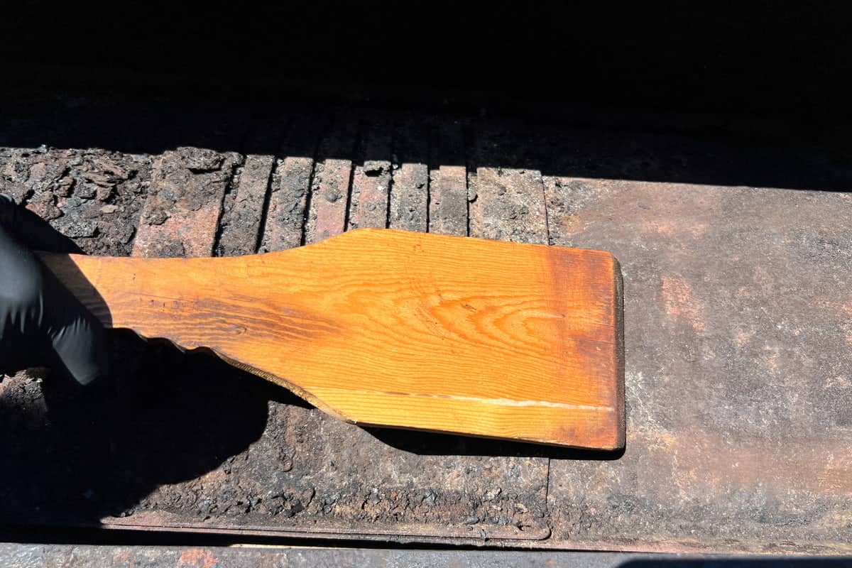 a wooden scraper scraping the flame broiler
