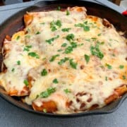 Smoked chicken enchiladas in a cast iron skillet