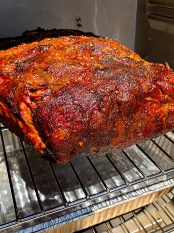 boston butt on the shelf of a masterbuilt electric smoker with a water pan beneath