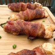 smoked jalpeno poppers wrapped in bacon on a cutting board