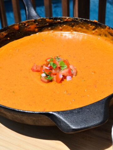 pit boss smoked queso in a cast iron skillet with pico de gallo on top