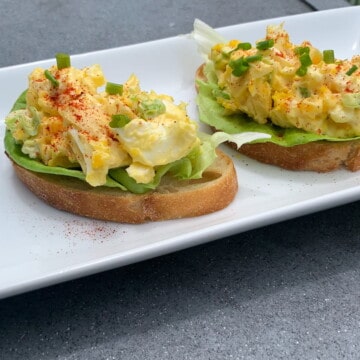 smoked egg salad on bread on a white plate