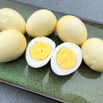 smoked eggs on a green platter with one cut open to reveal the yolk inside