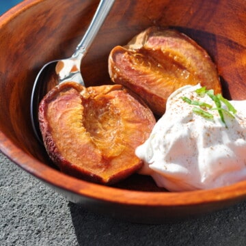 smoked peaches in a bowl with whipped cream on the side