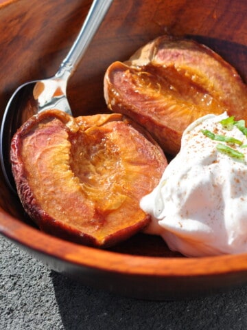 smoked peaches in a bowl with whipped cream on the side
