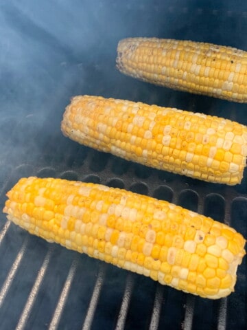 corn smoking on the grate of a treager pellet grill