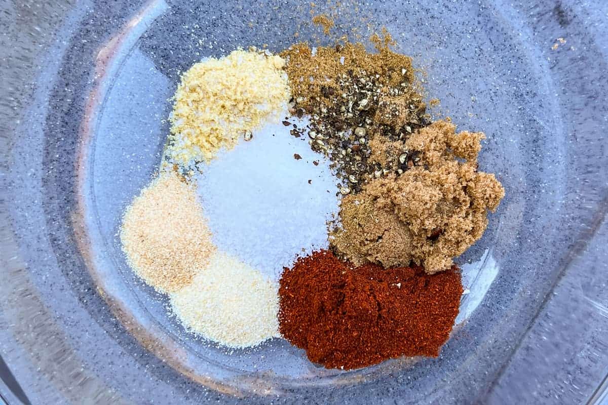 homamade BBQ rub ingredients in separate piles in a glass bowl