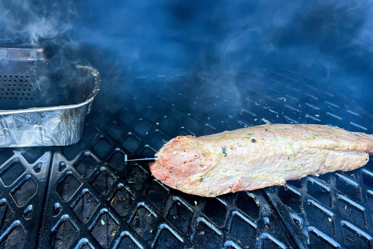 a MEATER thermometer in the pork on the grates of the grill