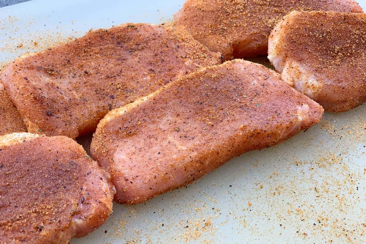 Raw pork chops seasoned with Three Little Pigs Championship BBQ Rub