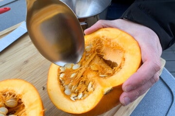 a metal spoon scooping out the seeds and pulp from a pie pumpkin