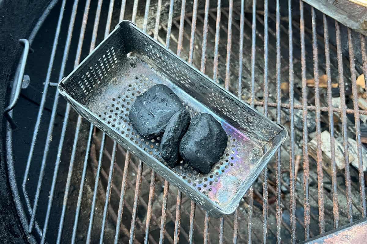 charcoal briquettes inside a smoker box on top of a charcoal grill