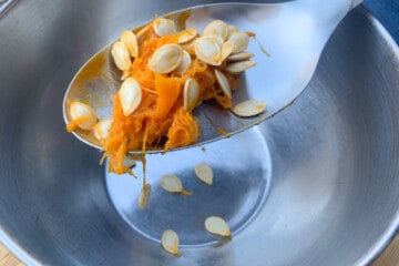 a spoon with pumpkin pulp and seeds