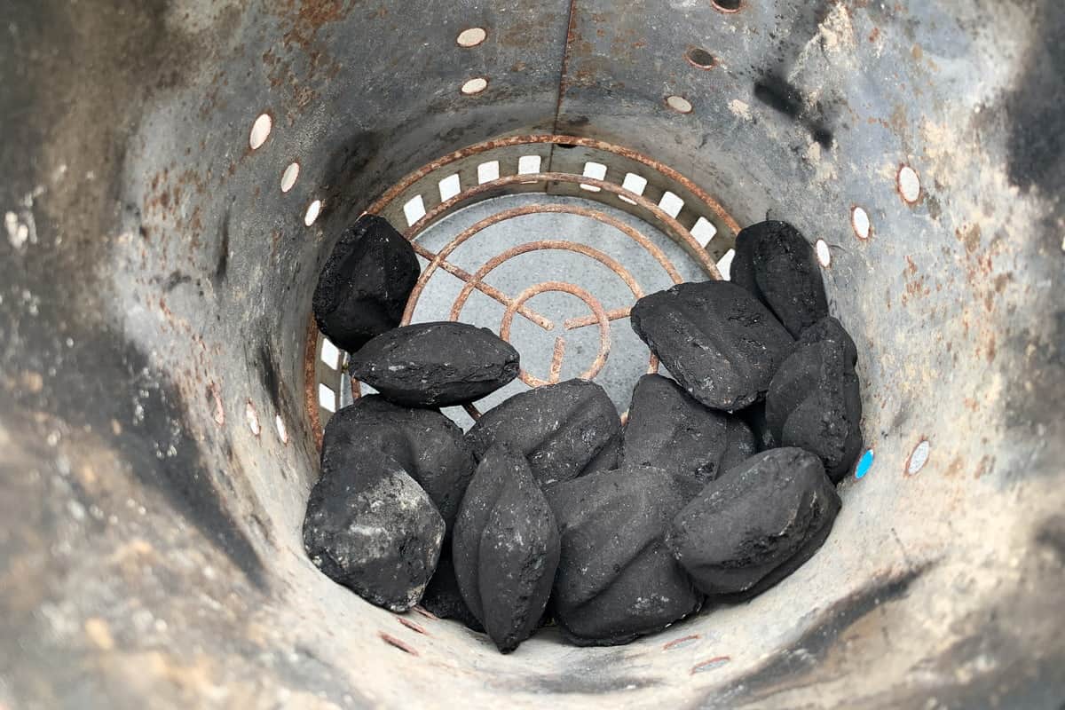 new charcoal briquettes in the bottom of a charcoal chimney