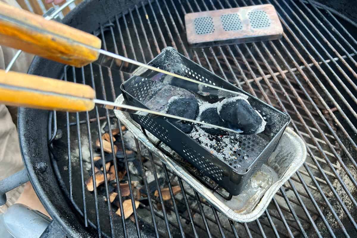 tongs turning over lit charcoal briquettes in the smoker box