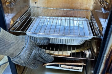 a aluminum foil pan filled with water on the bottom shelf of a masterbuilt electric smoker