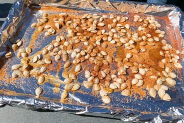 pumpkin seeds on a foiled lined baking sheet that have been sprinkled with BBQ rub