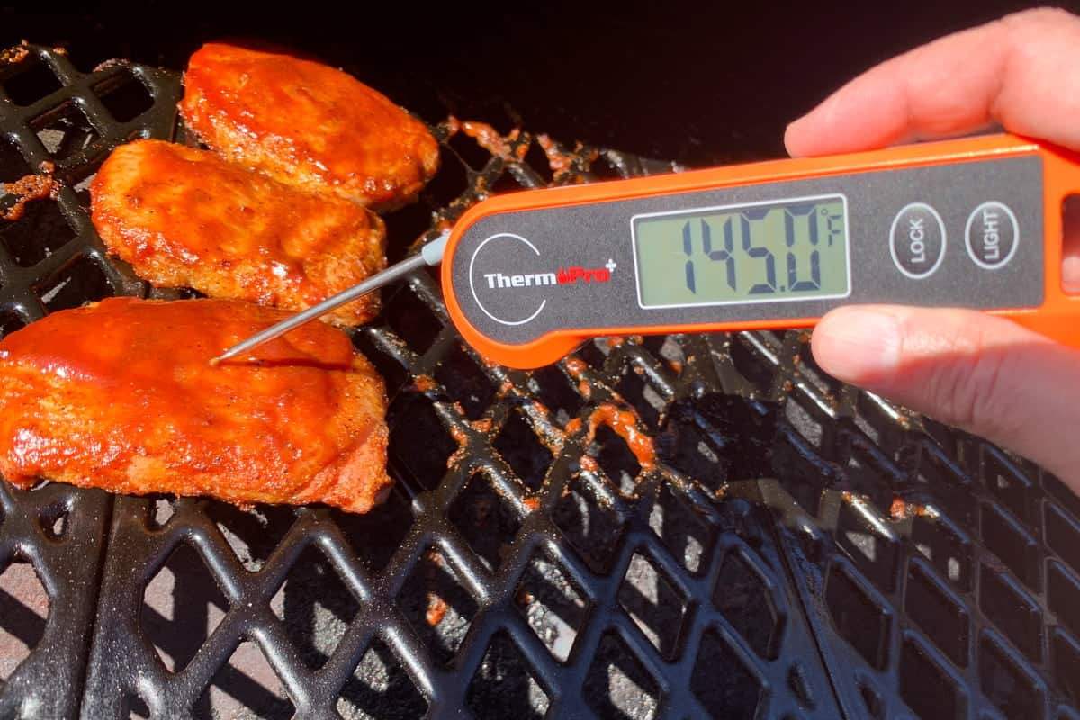 instant read thermometer inserted into a boneless pork chop reading 145 degrees F
