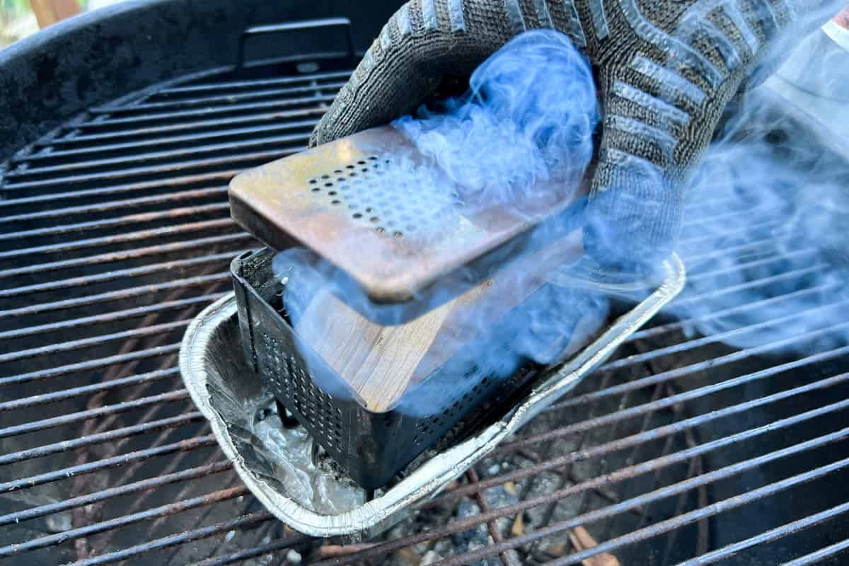 a gloved hand placing the lid on top of the smoking smoker box
