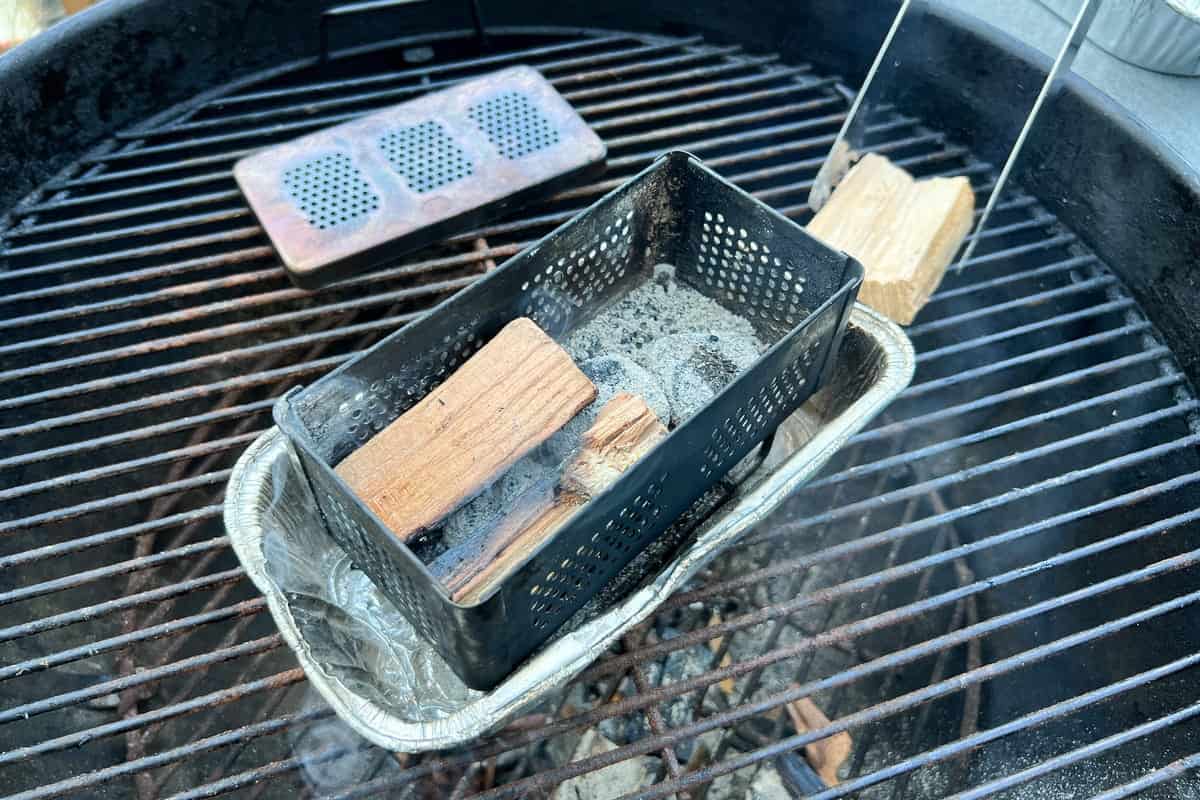 tongs moving wood around inside the lit smoker box