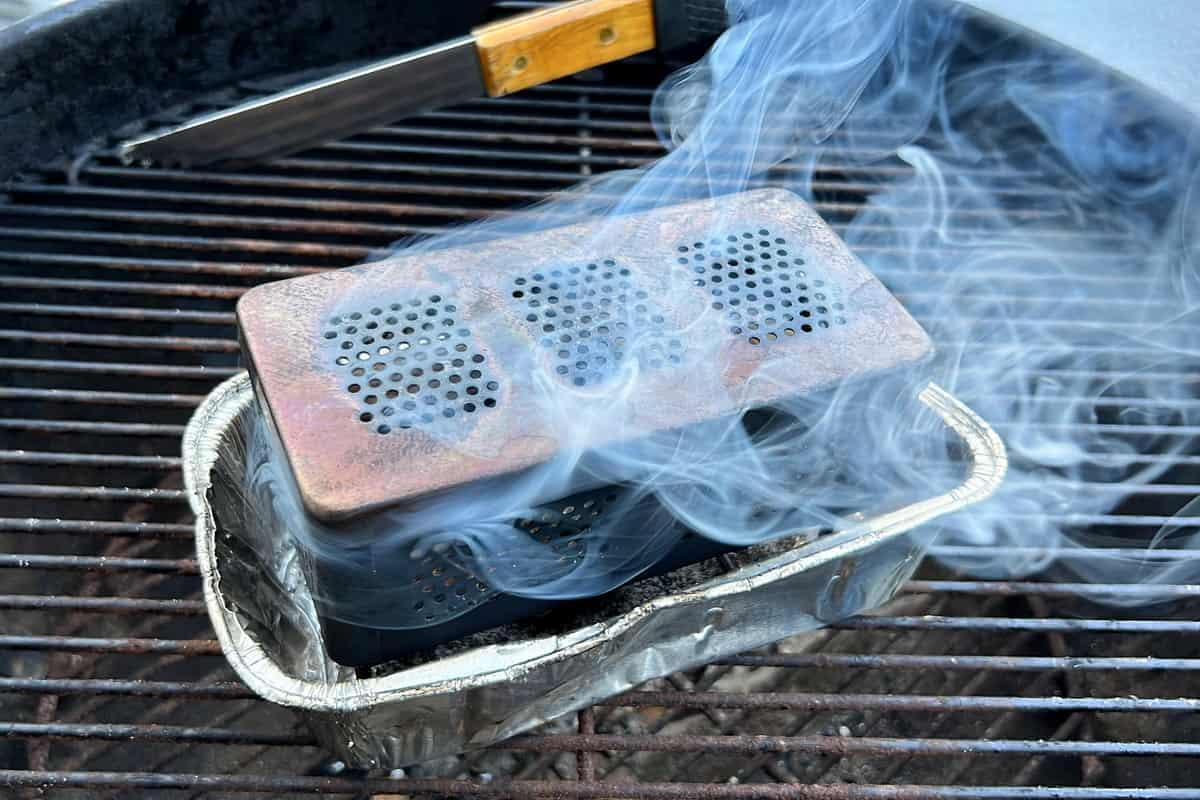 smoker box with lid on top and smoke billowing out