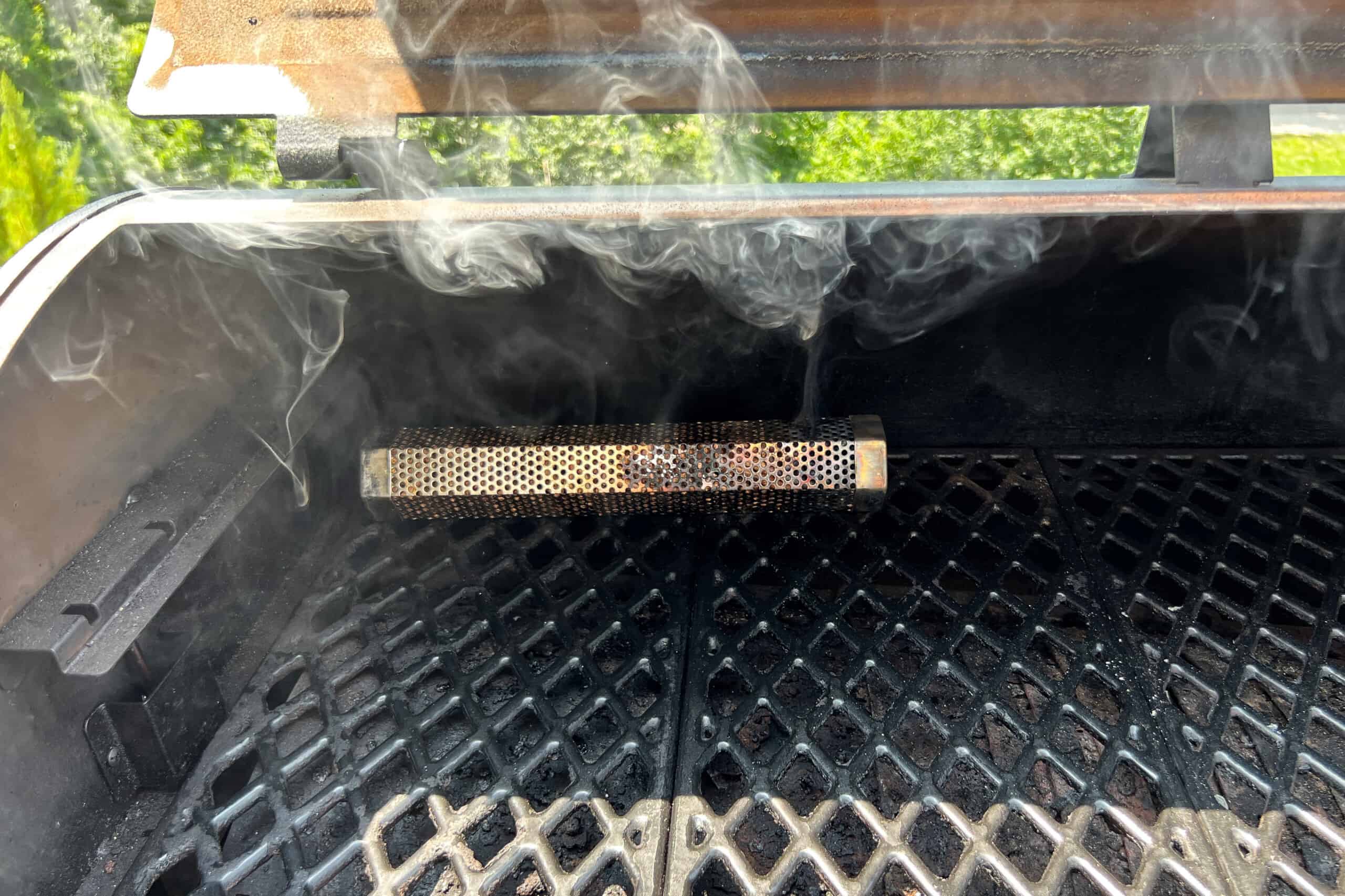 a lit pellet tube smoker near the back left of the pellet grill