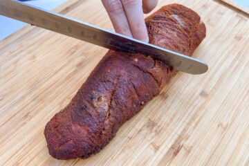 a meat slicing knife cutting through the pork tenderloin