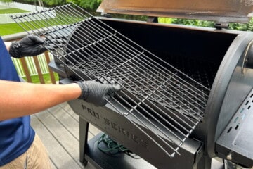 holding the pit boss top rack at a diagonal to slide it into the grill