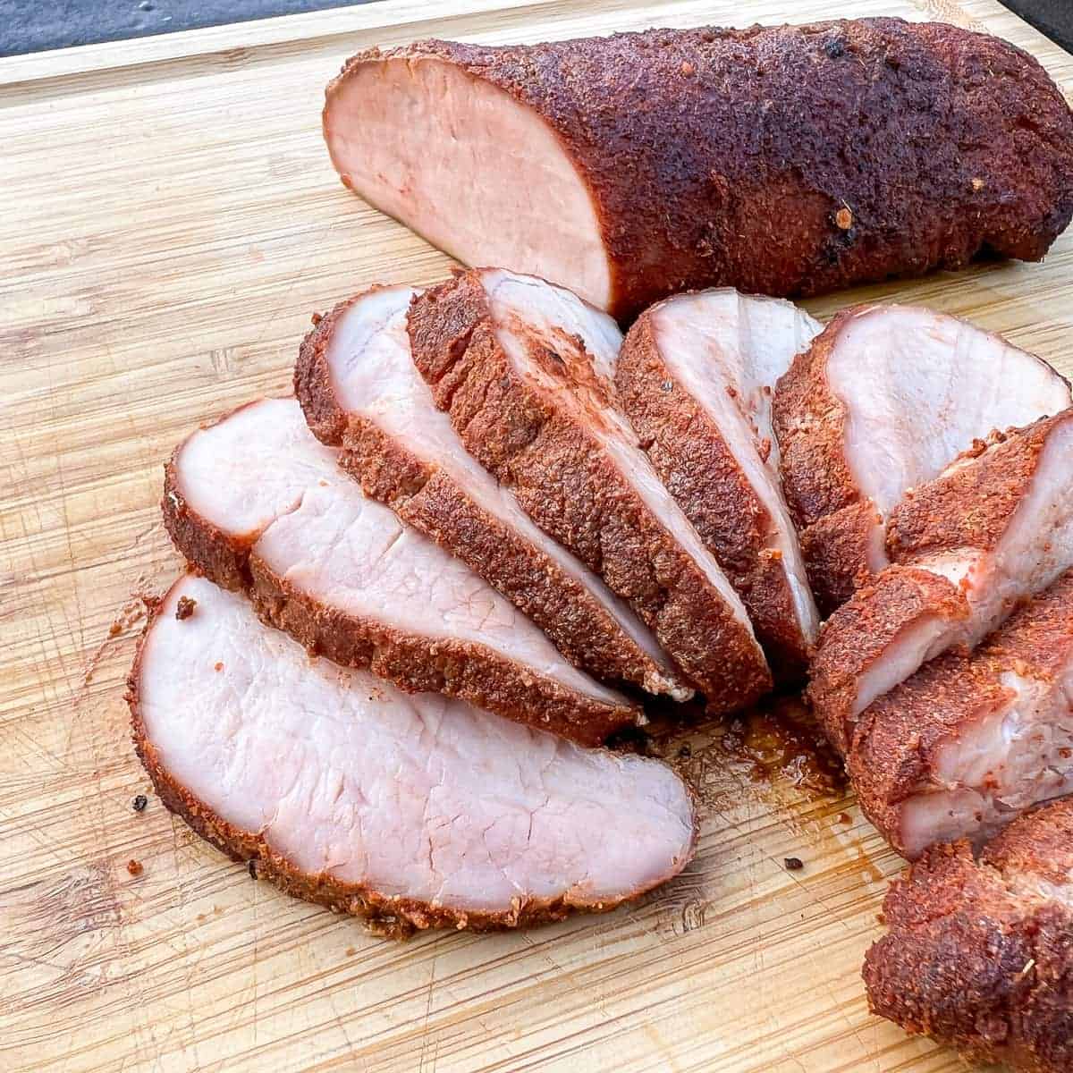 smoked pork tenderloin sliced on a cutting board