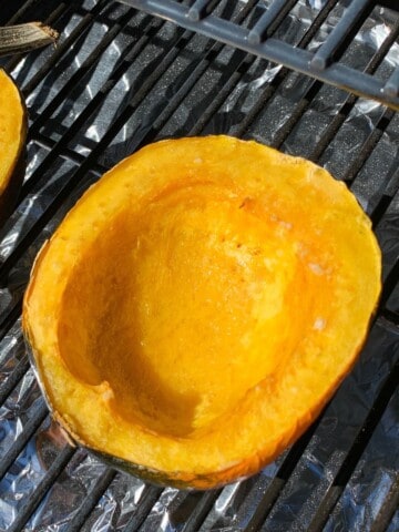 smoked acorn squash on the grates of a pellet grill