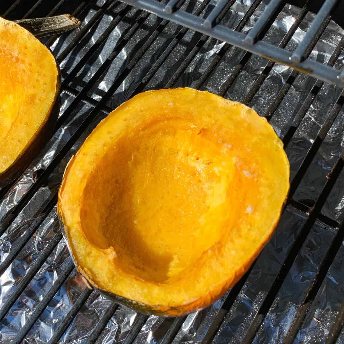 smoked acorn squash on the grates of a pellet grill