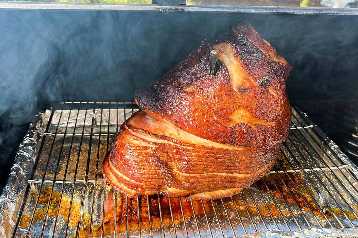 a ham being smoked for a second time on a wire rack over a baking sheet on a pellet grill