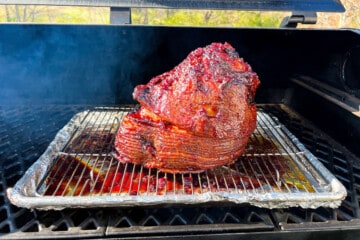 glazed double smoked ham on a wire rack baking sheet combo on the grates of a Pit Boss pellet grill