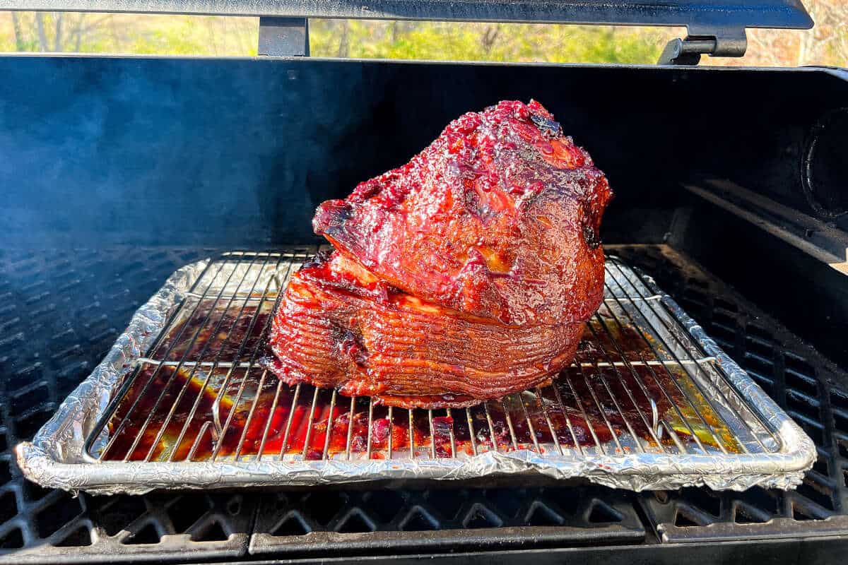glazed double smoked ham on a wire rack baking sheet combo on the grates of a Pit Boss pellet grill