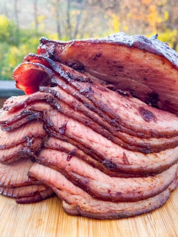 Double smoked ham with a cherry glaze on a cutting board to show the slices of ham