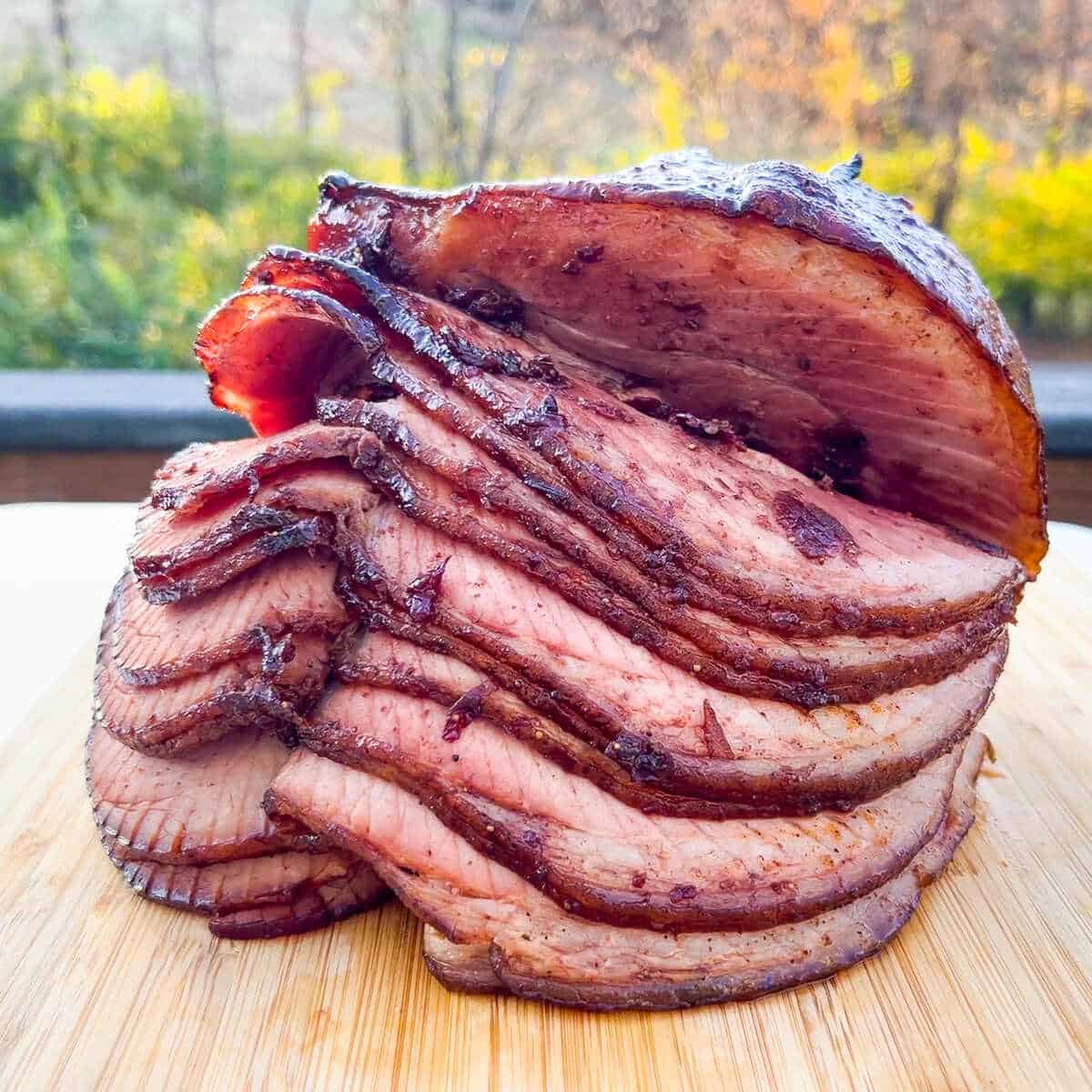 Double smoked ham with a cherry glaze on a cutting board to show the slices of ham