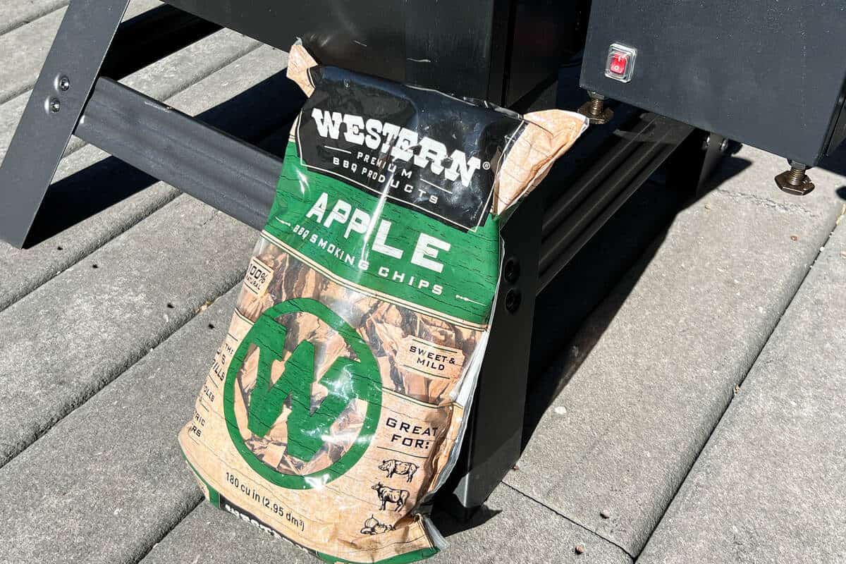 a bag of apple wood chips in front of a Masterbuilt electric smoker