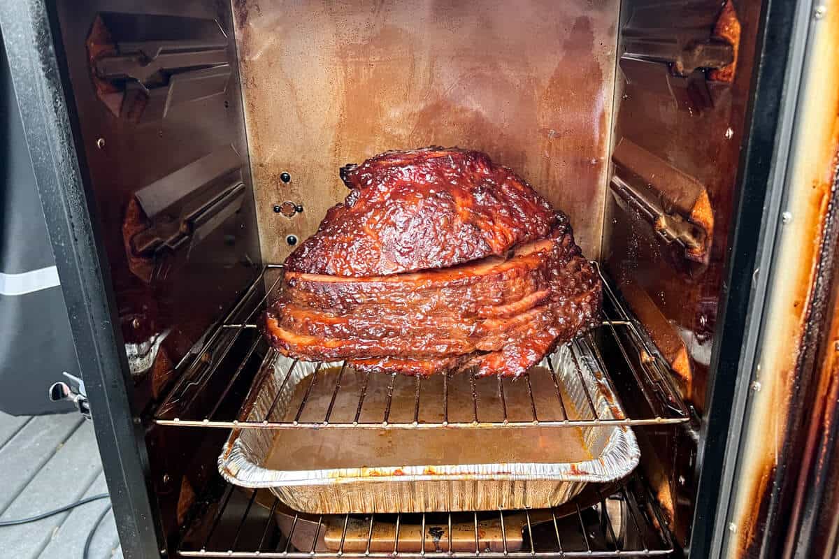 a glazed ham smoking in a Masterbuilt electric smoker