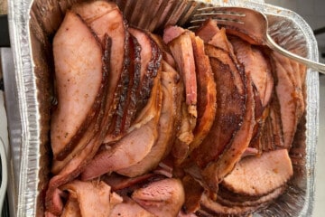 slices of glazed double smoked ham in an aluminum foil pan for serving