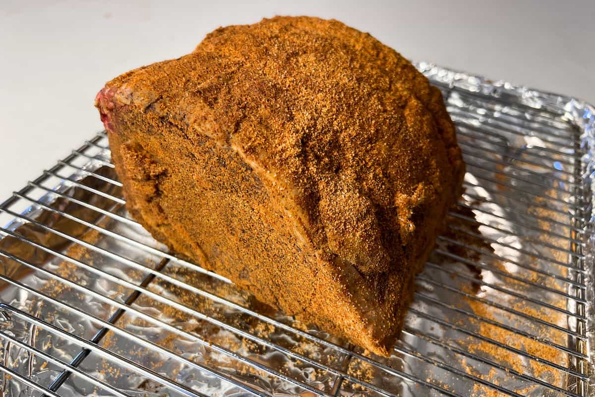 a seasoned raw ribeye roast on a baking sheet