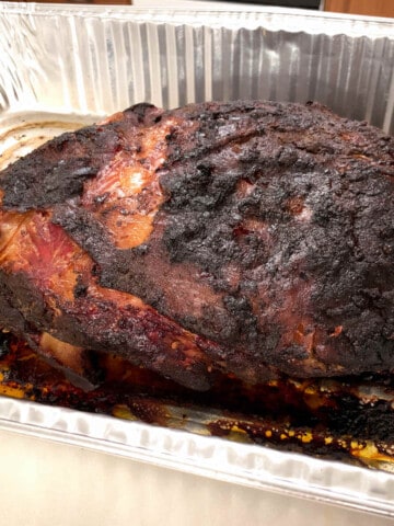 a cooked pork butt in an aluminum foil pan