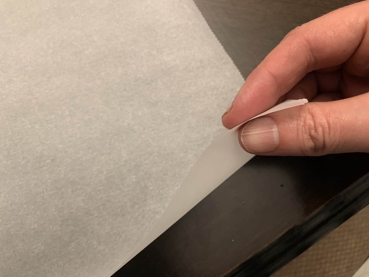 a hand holding the edge of a sheet of parchment paper