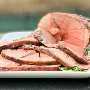 sliced leg of lamb roast on a white plate