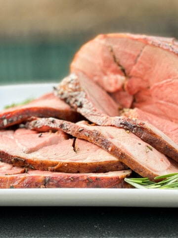 sliced leg of lamb roast on a white plate