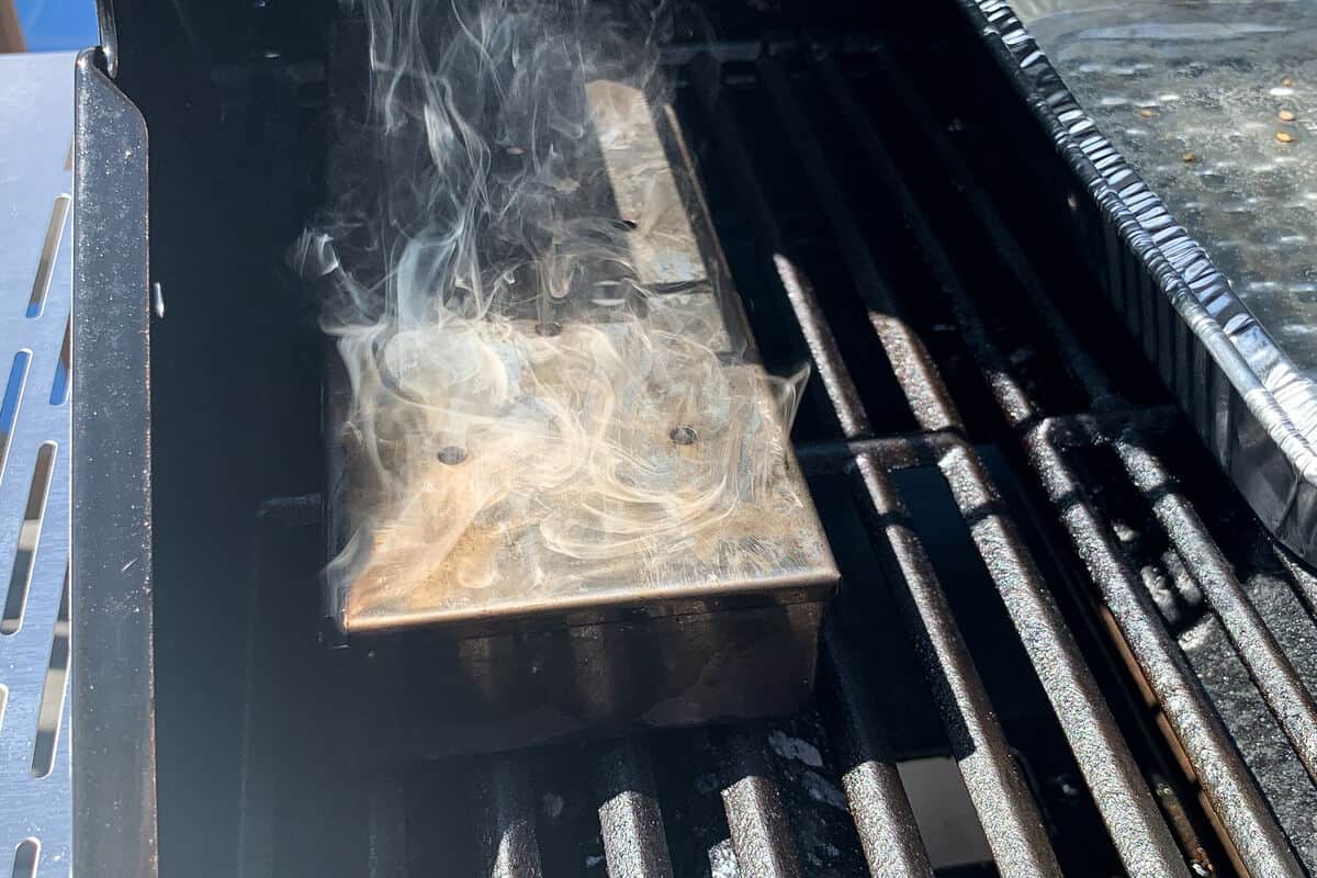 a smoker box smoking on a gas grill